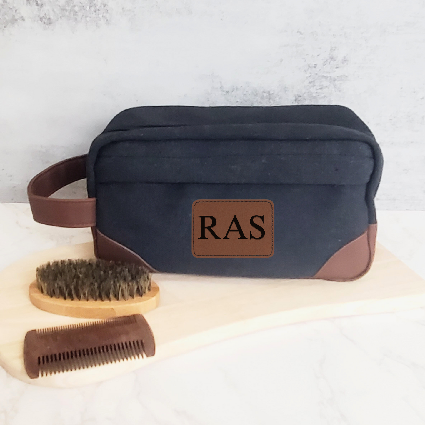 Black men's toiletry bag with brown leather accents and handle.  Engraved with 3 initials on brown leather patch.