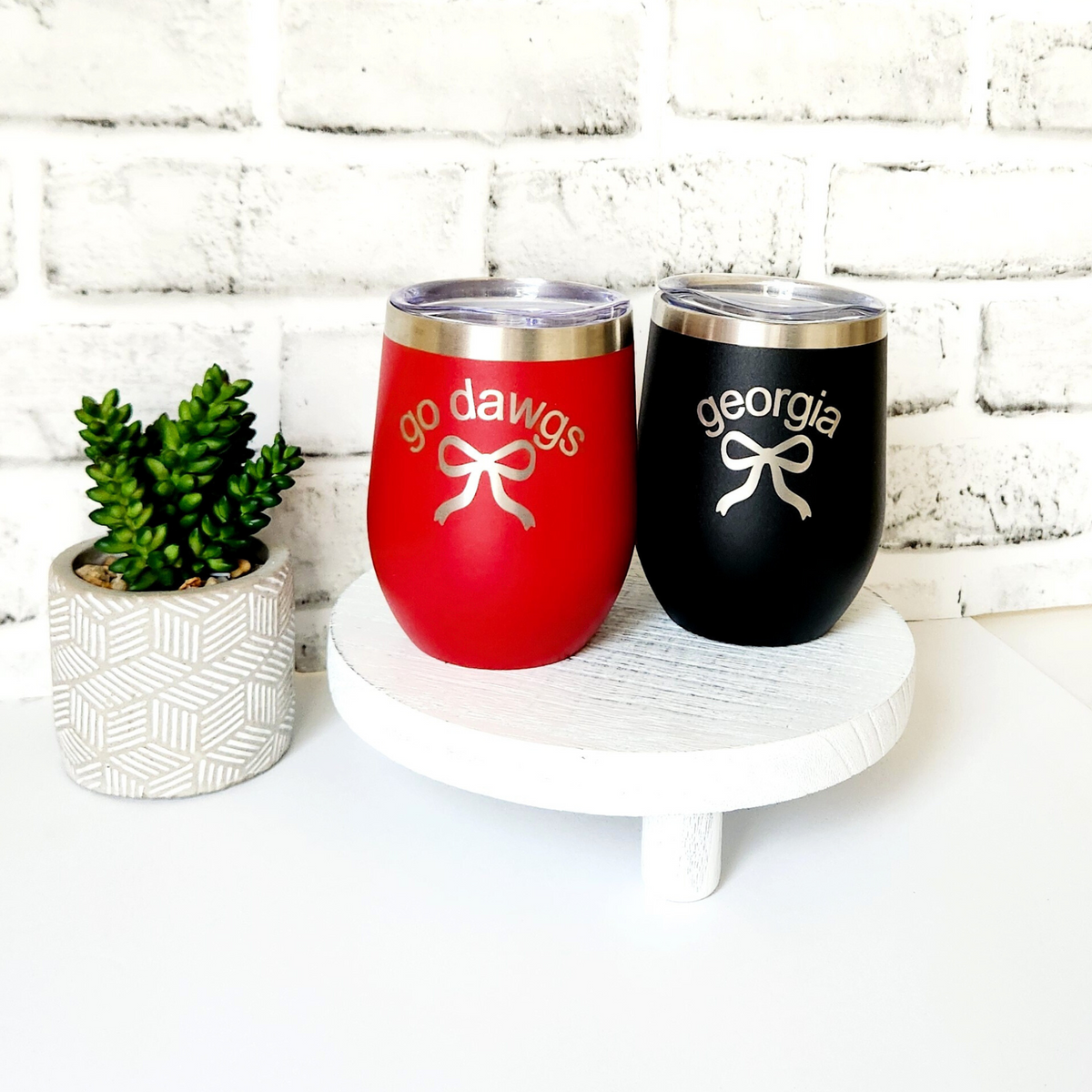 Two insulated tumblers, one red and one black, with 'go dawgs' and 'georgia' text on a white surface.