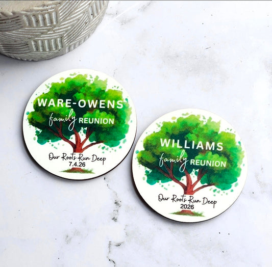 Two round family reunion magnets with 'Ware-Owens' and 'Williams' family name and 'Our Roots Run Deep' and event date with green tree in the background. Magnets are on marble table background.