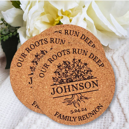 A round cork coaster with personalized engraving that includes a last name and a date, placed on a white surface with a flower arrangement in the background.