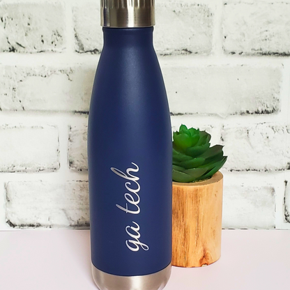 Blue insulated bottle with 'go tech' text next to a small potted plant on a white brick background