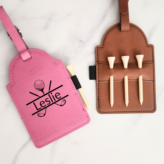 Pink personalized “Leslie” golf bag tag beside a tan tee holder with three wooden tees.