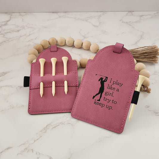 Pink Golf Tag engraved with lady swinging a golf club silhouette and the words " I play like a girl, try to keep up."  The back of the golf tag has 3 wooden golf tees in a holder.