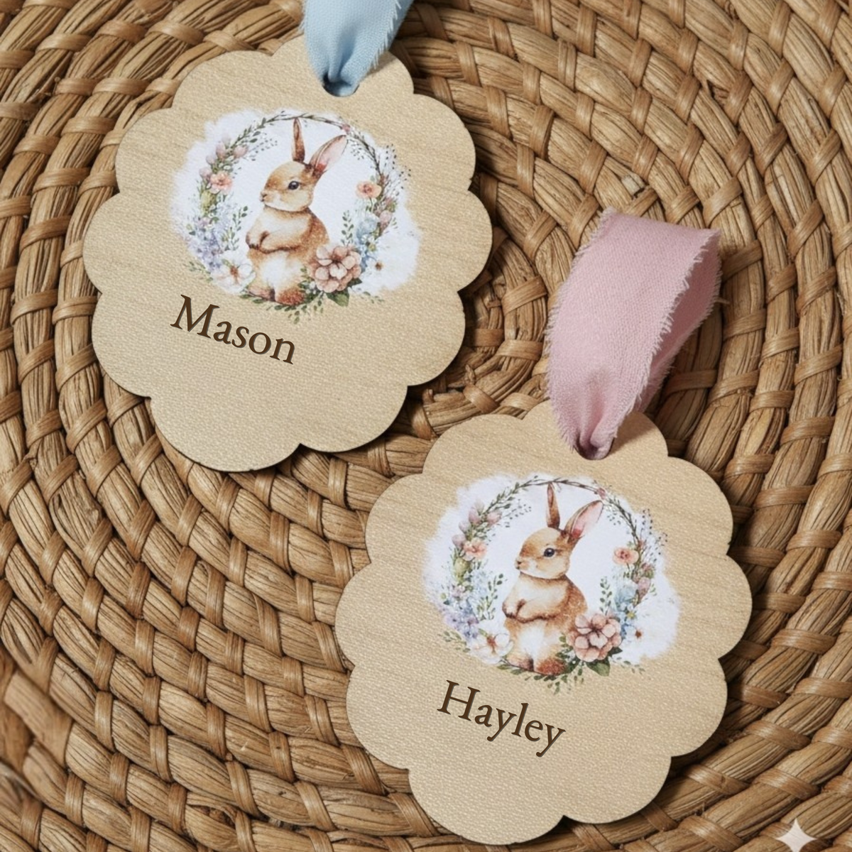 Personalized wooden Easter basket tags with bunny illustration and engraved names Mason and Hayley, tied with blue and pink ribbon on woven basket background.