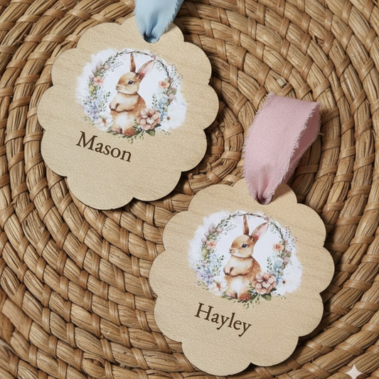 Personalized wooden Easter basket tags with bunny illustration and engraved names Mason and Hayley, tied with blue and pink ribbon on woven basket background.